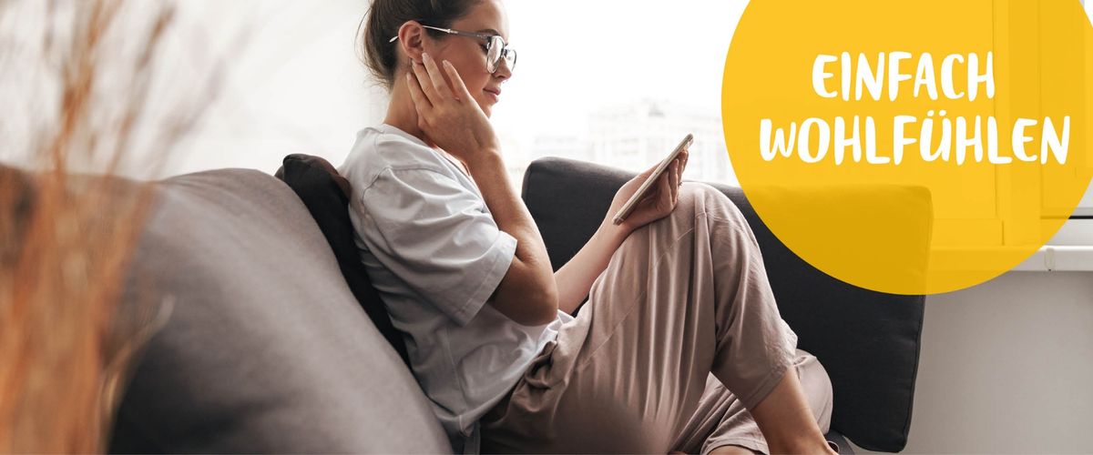 Frau sitzt entspannt auf dem Sofa mit Tablet – daneben Text: ‚Einfach wohlfühlen. Einfach wohlfühlen